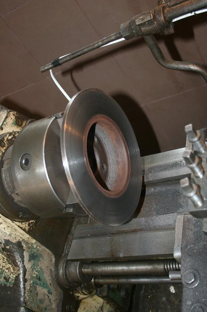 Vented cast iron brake disc rotor being machined on industrial equipment