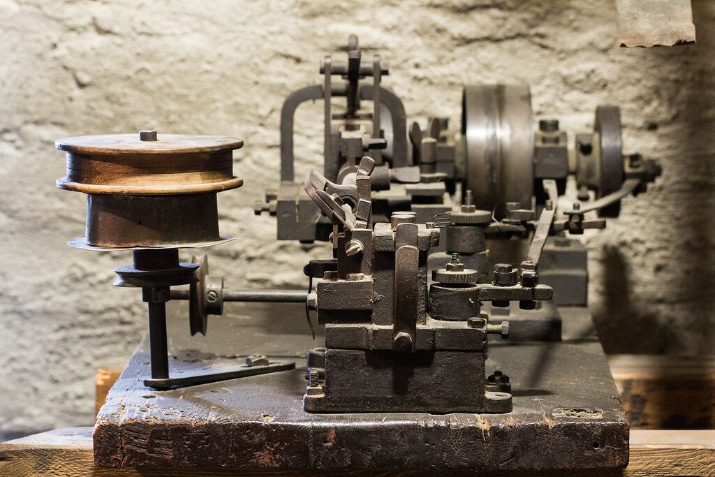 Vintage industrial machinery with metal components and wooden spool on workbench